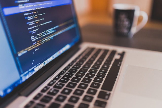 Laptop with code on screen next to a coffee mug on a desk