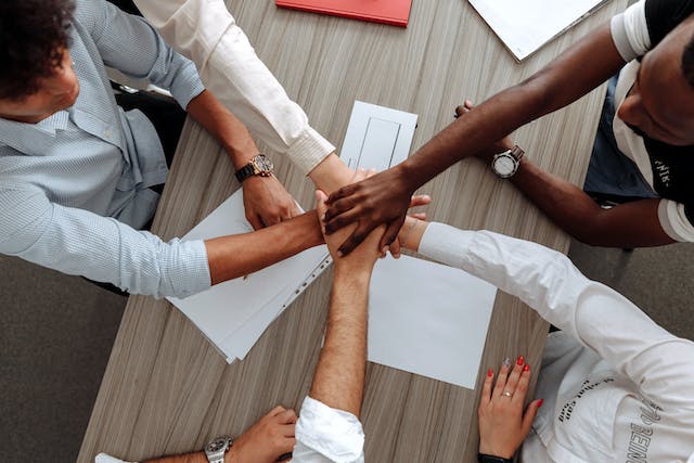 Team members stacking their hands together over a meeting table
