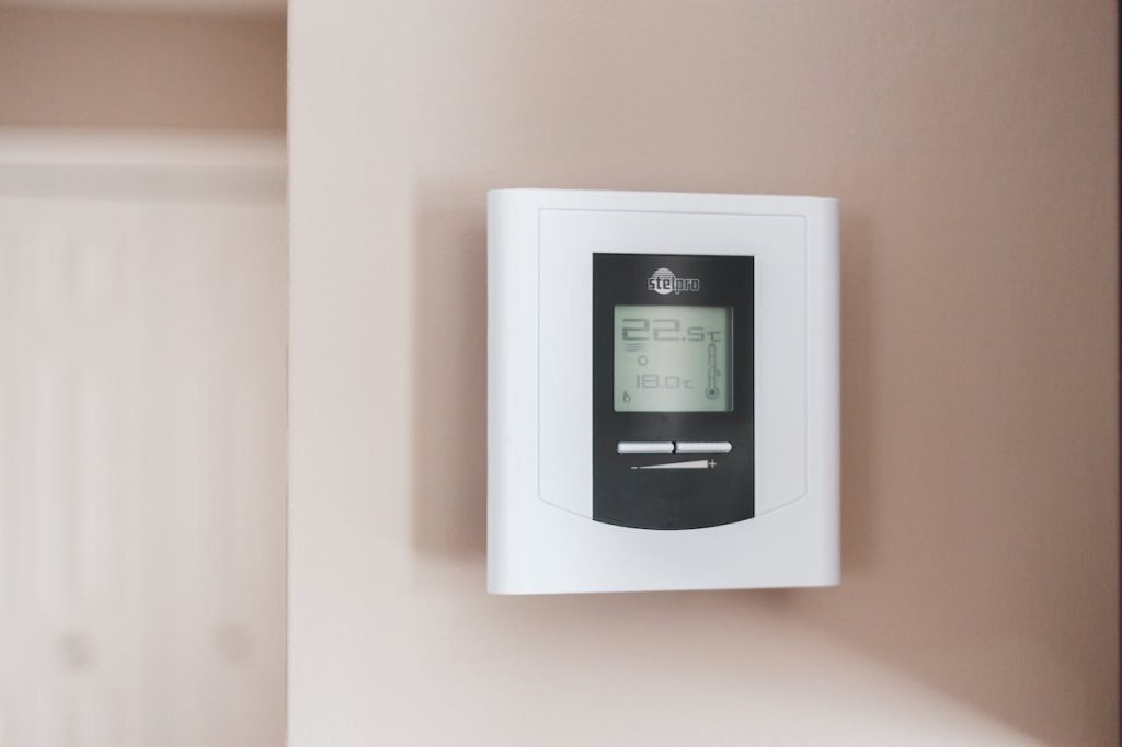 Wall-mounted digital thermostat displaying room and target temperatures