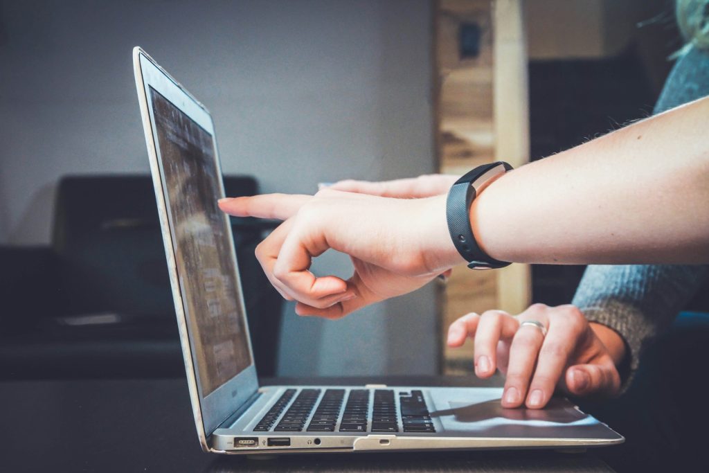 Two people at a laptop, one pointing at the screen