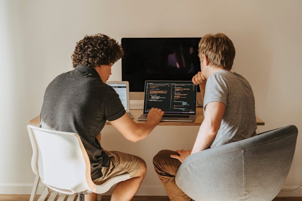 Two developers working through code together on a laptop at a shared desk