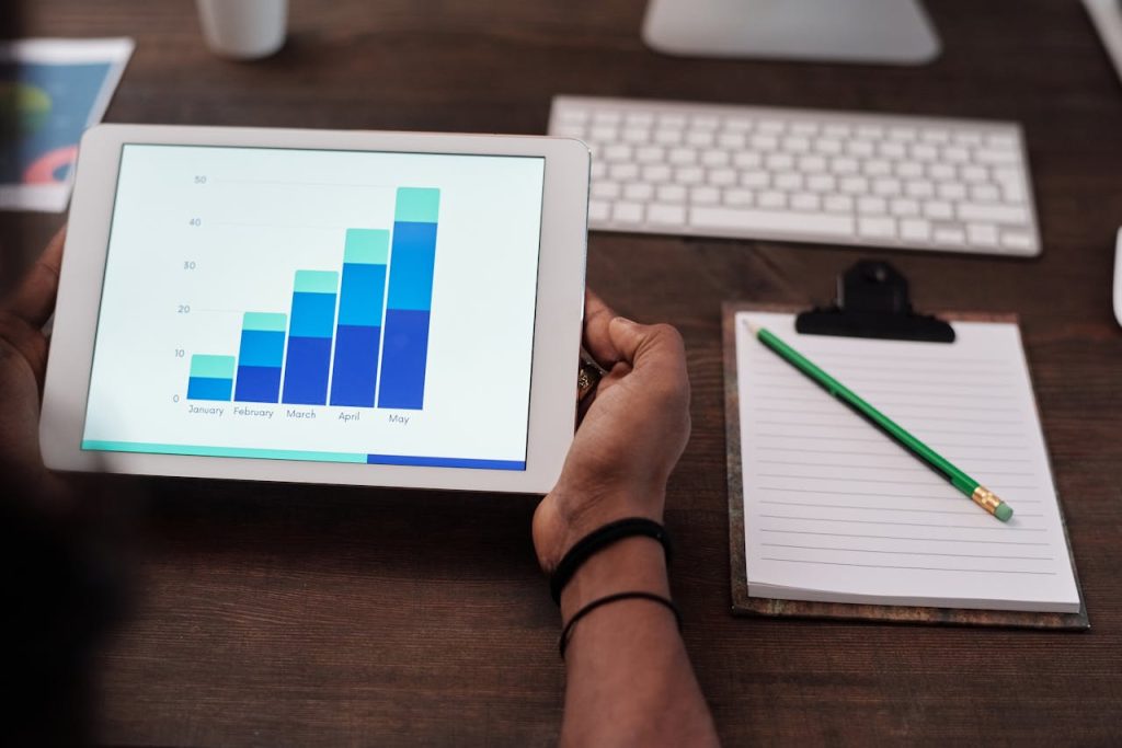 Hands holding a tablet showing a bar chart rising from January to May