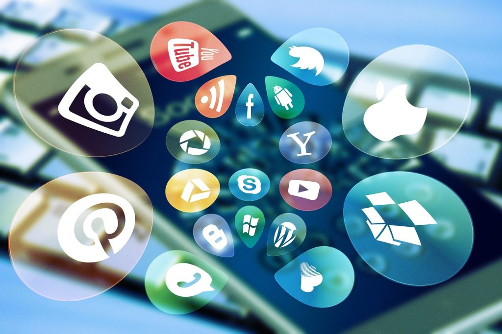 Social media and app icons floating over a blurred smartphone and keyboard